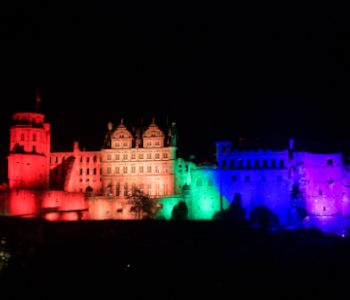 Auf dem Foto ist das Heidelberger Schloss in Regenbogenfarben. Die Regenbogenfarben stehen für Vielfalt und Frieden. Die Regenbogenfarben sind ein Symbol von queeren Menschen