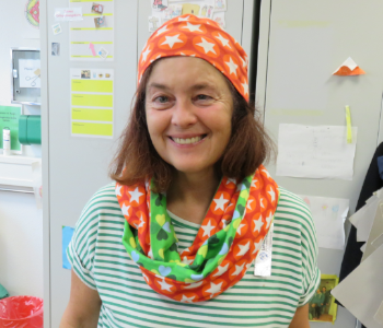 Das Foto zeigt Karin Weiher. Sie hat eine selbst genähte Mütze und Schal an. Mütze und Schal sind bunt.