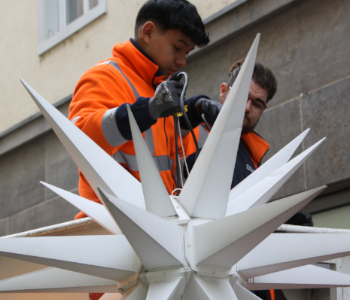 Zwei Arbeiter der Stadtwerke Heidelberg ist auf der elektrischen Leiter. Er hält einen Stern in der Hand.