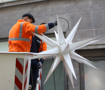 Zwei Arbeiter der Stadtwerke Heidelberg ist auf der elektrischen Leiter. Sie befestigen einen Stern.