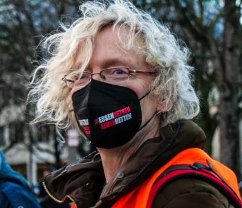 Das Foto zeigt Friederike Benjes bei einer Portestaktion. Sie trägt eine Corona-Schutzmaske. Auf der Maske steht: Essen retten. Leben retten.