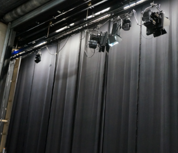 Foto von einem Vorhang und Lichtstrahlern hinter der Bühne.